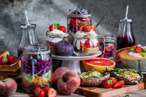 Färgglada burkar med frukt och grönsaker, perfekta för ett somrigt brunch recept. Jordgubbar, blåbär, kål och quinoa i lager.