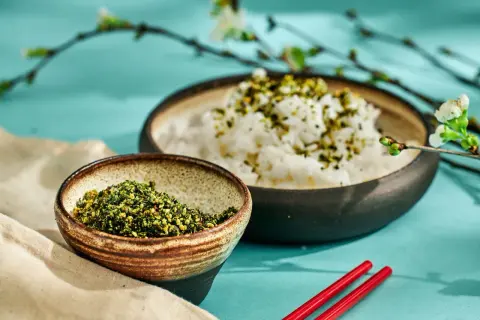En skål med ris toppad med gröna kryddor, bredvid en skål med samma kryddblandning. Perfekt för ett umami recept.