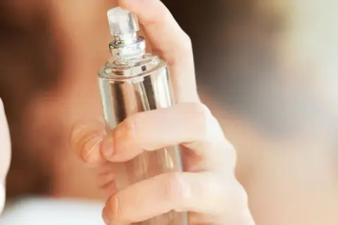 Eine Hand hält einen Glasflakon, bereit, einen selbstgemachten Erfrischungsspray aufzusprühen.