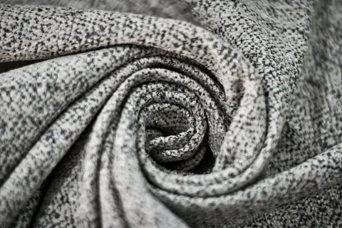 Graues, gemustertes Polyester-Material, kunstvoll zu einer Spirale gedreht.