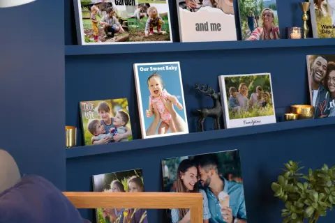 Schöne Fotowand Ideen mit Familienfotos auf blauen Regalen. Ein Baby, Kinder und Paare lächeln von den Bildern.