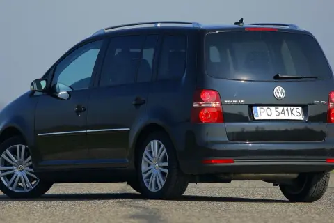 Ciemny Volkswagen Touran 2.0 TDI na drodze, widok z tyłu i boku.