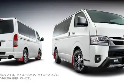 Dwa białe vany Toyota Hiace z pakietem GR Parts. Jeden z tyłu, drugi z przodu, oba z czerwonymi chlapacami.
