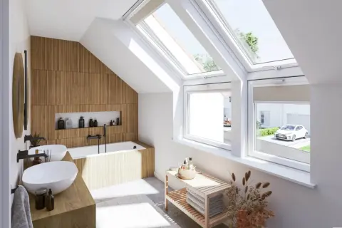Salle de bain sous pente lumineuse avec murs en bois, baignoire, double vasque et grandes fenêtres de toit offrant une vue sur un jardin.