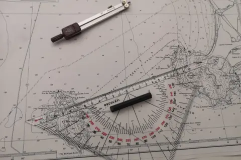 Strumenti nautici su una carta: compasso, righello graduato e goniometro. Un esempio di come leggere latitudine e longitudine.