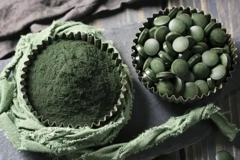 Proszek i tabletki z chlorelli. Choć suplementacja jest popularna, warto znać potencjalne chlorella skutki uboczne.