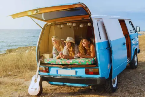 Tres amigas disfrutan de la vida en su furgoneta camperizada junto al mar. Inspiración para saber como camperizar una furgoneta.