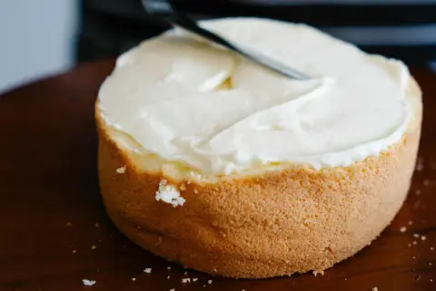 Bizcocho esponjoso cubierto con glaseado blanco cremoso, listo para decorar. Una deliciosa receta bizcocho.