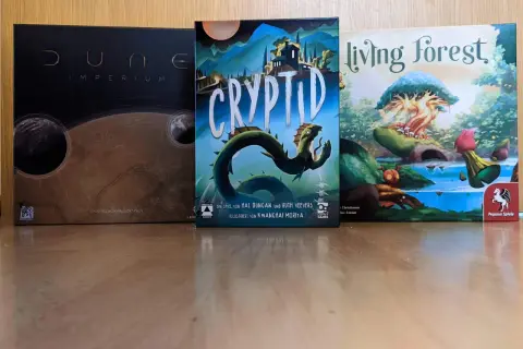 Drei Brettspiele: Dune: Imperium, Cryptid und Living Forest. Diese Spiele sind Kandidaten für den kritikerpreis spiel des jahres.