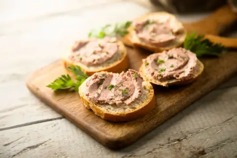Leberwurstbrote auf Holzbrett. Vorsicht bei Leberwurst in der Schwangerschaft wegen Vitamin-A-Überdosierung.