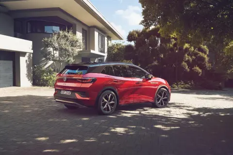 Röd elbil parkerad på uppfart framför modernt hus. En dag för att fundera på hur många elbilar som finns i Sverige.