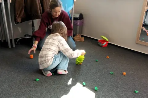 Terapeuta pomaga dziecku w zabawie, która jest częścią wczesnego wspomagania rozwoju.