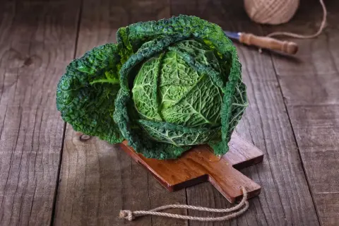 Ein frischer Wirsingkopf liegt auf einem Holzbrett, bereit für leckere Wirsing Rezepte.