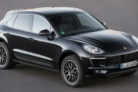 Czarny Porsche Macan na ciemnym tle. Choć piękny, warto znać jego potencjalne wady przed zakupem.