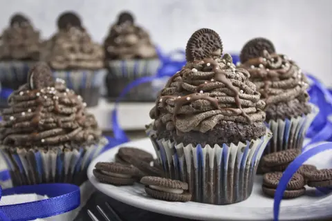 Schokoladen-Muffins mit Oreo-Creme-Topping, garniert mit ganzen Oreos und Schokoladensauce. Ein Genuss für alle Oreo-Fans!