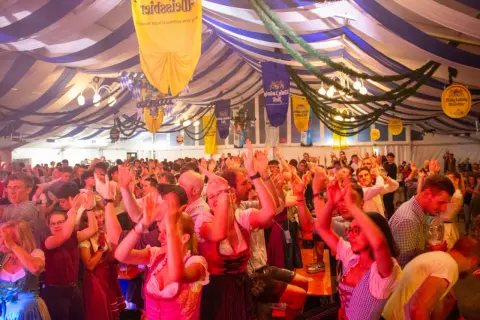 Fröhliche Menschen im Festzelt, die auf einer Veranstaltung in Pasing tanzen und jubeln.