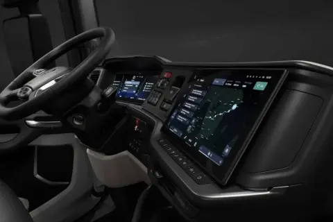 Vue du scania interieur cabine, avec volant, écrans tactiles affichant navigation et informations, et tableau de bord moderne.