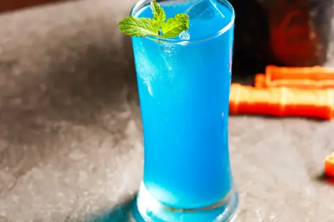 Błękitny drink z miętą, lodem i pomarańczowymi dodatkami. Ten orzeźwiający kamikaze shot wygląda jak letnia bryza.