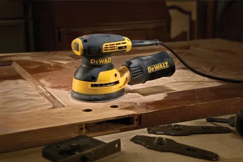 Szlifierka mimośrodowa DeWalt w akcji, pokazująca, jak działa, podczas renowacji drewnianych drzwi.