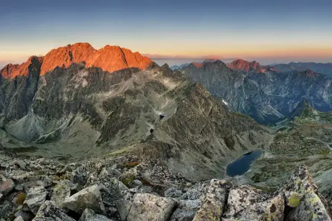 Zachód słońca nad najwyższym szczytem Tatr, Gerlachowskim, oświetla skaliste zbocza i górskie jeziora.