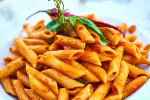 Penne w pikantnym sosie pomidorowym, ozdobione papryczką chili i bazylią. Danie wygląda jak makaron Gigi Hadid, idealne na szybki lunch.
