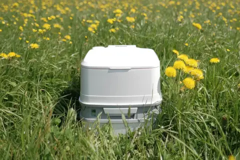 Un inodoro portátil blanco en un campo de flores amarillas. Así es como funciona un poti, una solución práctica para la naturaleza.