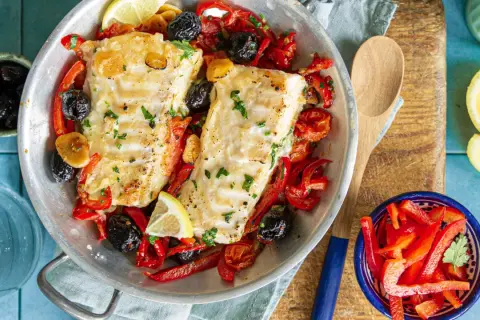 Délicieuse recette cabillaud aux poivrons rouges, olives noires et citron, servie dans un plat en métal.