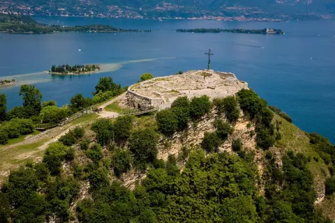 Rocca di Manerba, un sito archeologico con rovine e una croce, domina il lago.