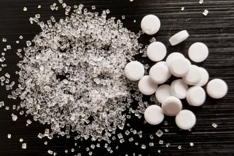 Sorbitol co to? Porównanie kryształków cukru i tabletek słodzika.