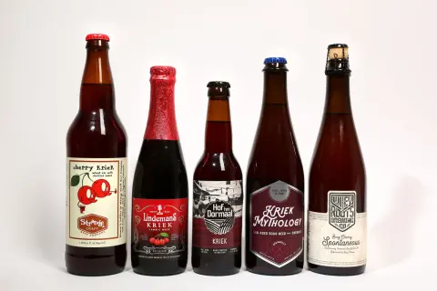 Pięć butelek belgijskiego piwa wiśniowego, w tym Kriek Mythology i Lindemans Kriek.