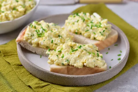 Pyszna pasta jajeczna jak dawniej, podana na kromkach chleba, posypana szczypiorkiem. Smak dzieciństwa na talerzu.