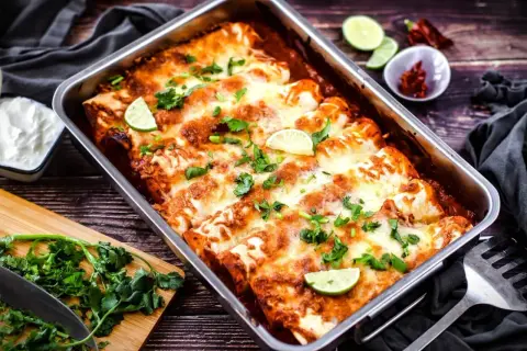 Herzhafte Enchiladas im Ofen, überbacken mit Käse und garniert mit Limettenspalten und Koriander. Ein tolles Enchiladas Rezept für jeden Anlass.