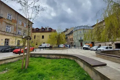 Plac rybny Lublin z kolorowymi kamienicami, zielenią i zaparkowanymi samochodami.