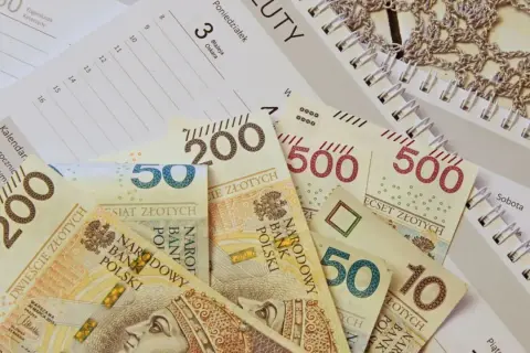 Polskie banknoty o nominałach 10, 50, 200 i 500 zł leżą na kalendarzu.