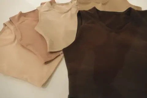 Kilka bezrękawnikowych bawełnianych t-shirtów w odcieniach beżu i brązu.