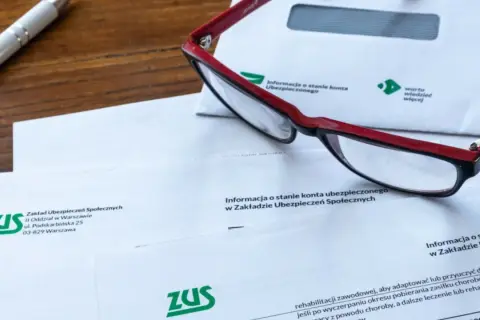 Okulary leżą na dokumentach ZUS, wśród których znajduje się wniosek o świadczenie rehabilitacyjne.