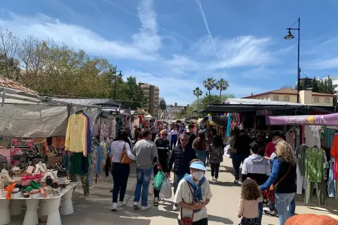 Folkmyller på marknad i Fuengirola. Stånd med kläder och skor längs en solig gata.