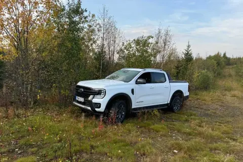 Vit Ford Ranger Wildtrak står parkerad vid en skogsväg. Kanske ett litet problem med terrängen?
