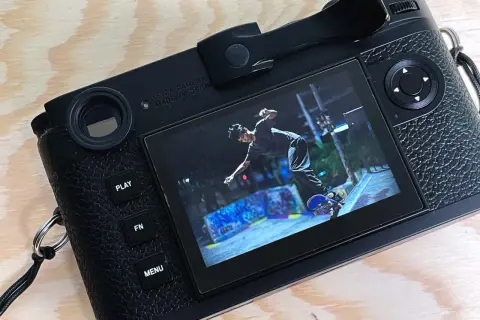 The Leica M11 displays a dynamic shot of a skateboarder mid-air at a graffiti-covered skatepark.