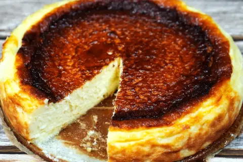 En krämig baskisk cheesecake med en härligt bränd yta, en bit är bortskuren.