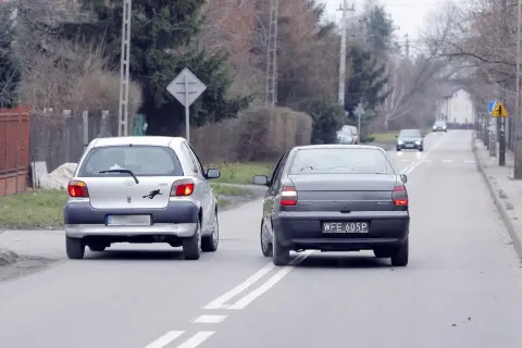 Srebrny samochód wyprzedza ciemny, jadący po tej samej drodze. Wymijanie i omijanie to kluczowe manewry na drodze.