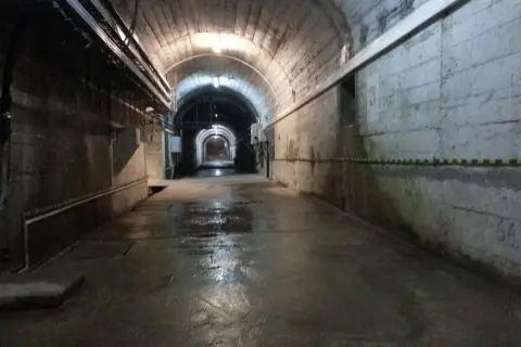 Wnętrze tunelu zapory Solina. Zwiedzanie cennik. Wilgotna posadzka, betonowe ściany, łukowe sklepienie z instalacjami.