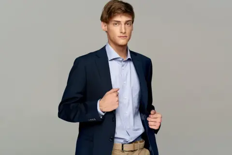 Elegancki mężczyzna w granatowej marynarce i błękitnej koszuli. Idealny przykład, jak ubrać się do klubu mężczyzna, by wyglądać stylowo i pewnie.