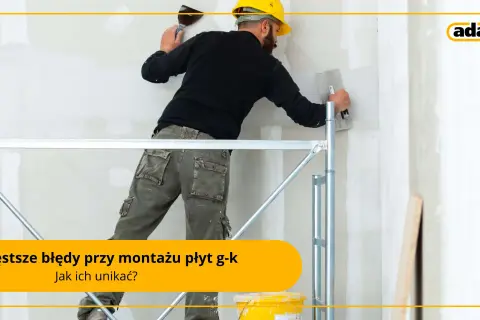 Pracownik na rusztowaniu wykonuje prace wykończeniowe przy ścianie z płyt g-k. Sucha zabudowa wymaga precyzji.