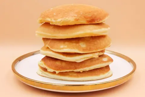 Stos puszystych, złotych pancake'ów na talerzu. Idealny przepis na śniadanie.