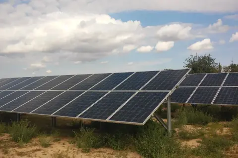Rzędy paneli fotowoltaicznych na tle błękitnego nieba z chmurami. Firma oferuje sprzedaż energii z fotowoltaiki.