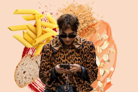 Frau im Leo-Mantel checkt ihr Handy, umgeben von Nudeln, Brot, Reis und Haferflocken. Sie fragt sich, wie viel Kohlenhydrate am Tag gesund sind.