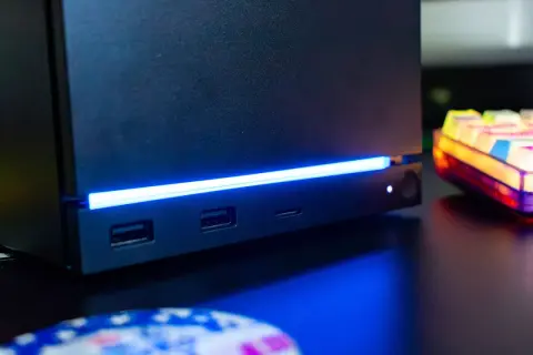 Czarny steam machine z niebieskim podświetleniem, portami USB i gniazdem na kartę SD. Obok kolorowa klawiatura.