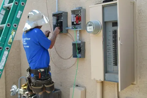 Elektryk pracuje przy skrzynce elektrycznej, podłączając przewody. To kluczowy etap instalacji, który zapewni odpowiednią moc przyłączeniową.