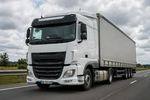 Camion blanc sur l'autoroute, le conducteur anticipe le freinage.